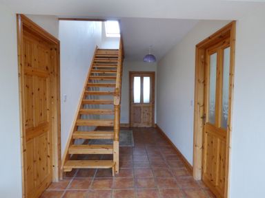 A hallway with tiled floor wooden doors and staircase at The Slate House in Cahersiveen County Kerry