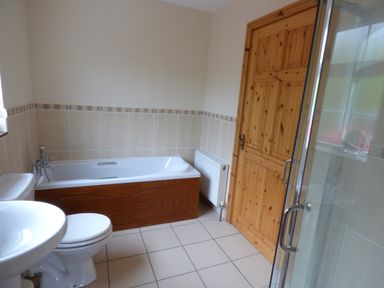 A bathroom with a bathtub toilet sink wooden door and shower at The Slate House in Cahersiveen County Kerry