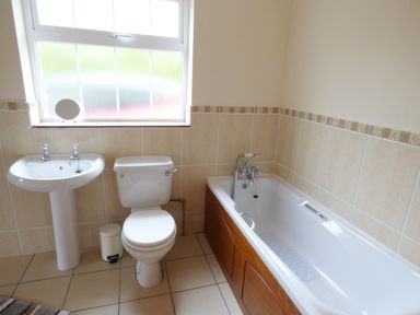 A bathroom with a sink toilet and bathtub with wooden paneling at The Slate House in Cahersiveen County Kerry
