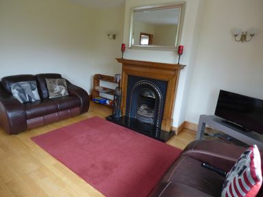 A living room with two leather sofas a fireplace with a mirror above and a television on a stand at The Slate House in Cahersiveen County Kerry
