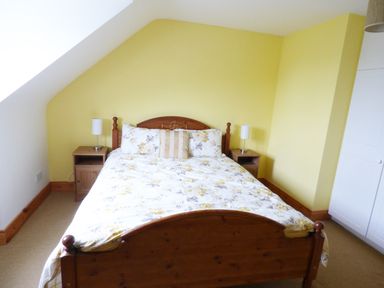 A bedroom with a wooden bed and two bedside tables with lamps at The Slate House in Cahersiveen County Kerry
