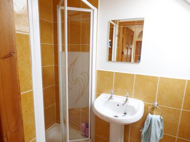 A bathroom with a shower enclosure sink mirror and towel ring at The Slate House in Cahersiveen County Kerry