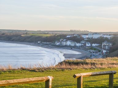 A coastal view with a curved beach and buildings along the shoreline at Flip Flops The Bay near Filey