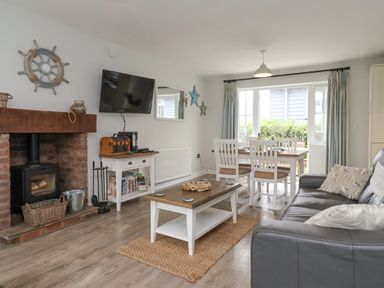 A living room with a fireplace television coffee table dining table and sofa at Flip Flops The Bay near Filey
