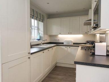 A kitchen with white cabinets a black countertop a sink a bread box and kitchen appliances at Flip Flops in The Bay near Filey