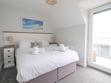 A bedroom with a double bed bedside tables and lamps with a glass door to a balcony at Flip Flops in The Bay near Filey