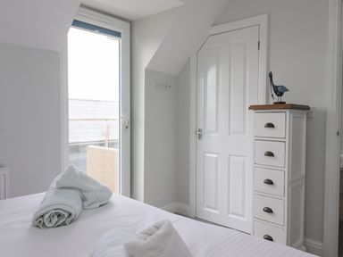 A bedroom with a bed and rolled towels near a glass door and a white chest of drawers with a decorative bird at Flip Flops The Bay near Filey