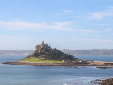An island with a castle on a hill surrounded by water at Chywolow Lodge in Penzance