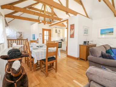 A dining area with a table and chairs next to a kitchen and living room at Mill in Nancegollan nr Porthleven
