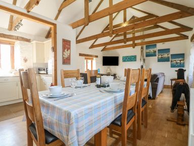 A dining area with a long table covered by a checked tablecloth and wooden chairs at Mill in Nancegollan nr Porthleven