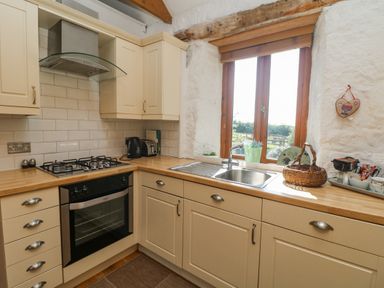 A kitchen with beige cabinets wooden countertop gas stove oven and a window above the sink at Mill in Nancegollan nr Porthleven