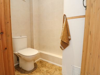A bathroom with a toilet and a brown towel hanging on a white wall at Mill in Nancegollan nr Porthleven