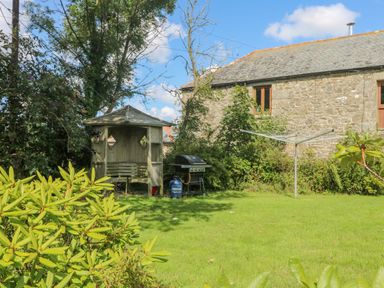 A garden with a wooden gazebo a gas barbecue a rotary clothesline and a stone building at Mill in Nancegollan nr Porthleven