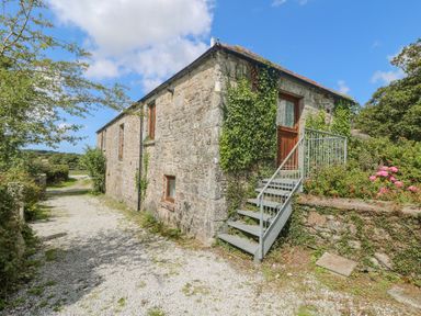 A stone building with ivy climbing the walls and metal stairs leading to a wooden door at Mill in Nancegollan nr Porthleven