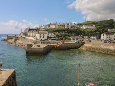 A coastal harbor with stone piers and houses on a hill at Mill in Nancegollan nr Porthleven