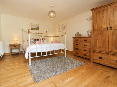 A bedroom with a metal bed frame, wooden wardrobe and chest of drawers at Mill Nancegollan nr Porthleven