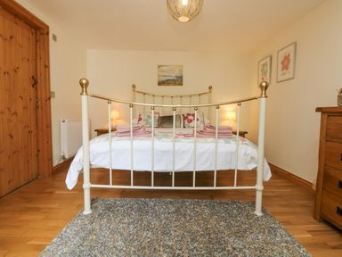 A bedroom with a metal bed frame a rug wooden furniture lamps and artwork on the walls at Mill in Nancegollan nr Porthleven