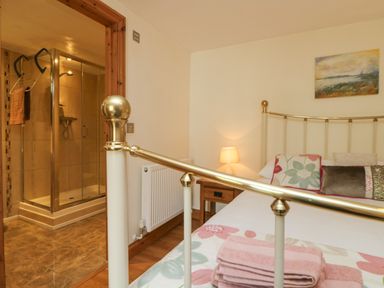 A bedroom with a brass bed frame pillows bedside table lamp and an adjacent bathroom with a shower at Mill in Nancegollan nr Porthleven