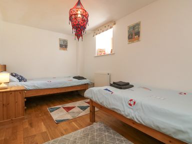 A bedroom with two single beds a bedside table with lamp and window at Mill in Nancegollan nr Porthleven