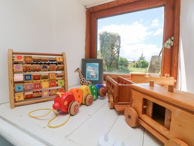 A windowsill with wooden alphabet blocks toy a wooden pull along caterpillar a giraffe figurine and wooden toy vehicles at Mill in Nancegollan nr Porthleven