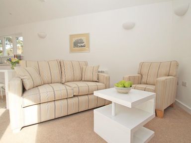 A living room with striped sofa armchair white coffee table and green apples at Cot Valley Cottage in St Just