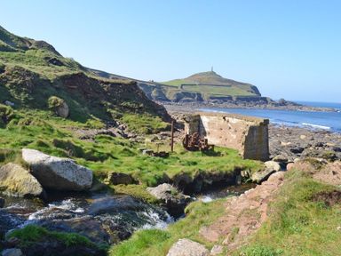 A rocky coastal landscape with a stream and old machinery near ruins at Cot Valley Cottage in St Just