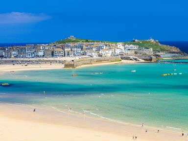 A coastal town with sandy beach boats and people walking by the water at Pippin in Lelant