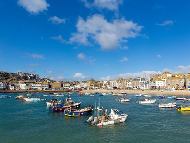 A harbor with boats in the water and houses along the shoreline at Pippin in Lelant