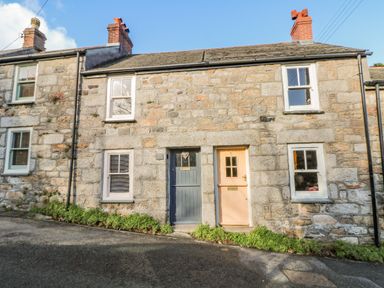 A stone cottage with two front doors and four windows on a sloped street at Pippin in Lelant