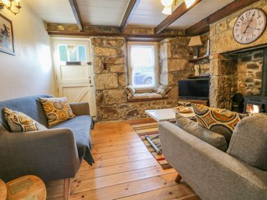 A living room with two sofas a wooden floor a small coffee table and a stone fireplace at Pippin in Lelant