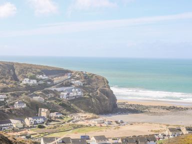 A coastal village with houses near cliffs and a beach at Ocean Blue in Porthtowan