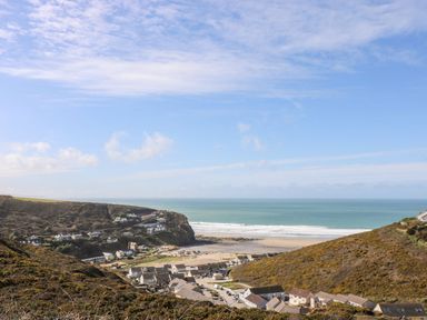 A coastal village with houses on hills and a beach with ocean waves at Ocean Blue in Porthtowan