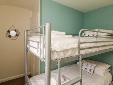 A bedroom with bunk beds and pillows with sailboat designs at Bayview in Watergate Bay