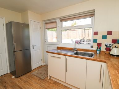 A kitchen with a stainless steel fridge sink wooden countertops and a door with a window at Bayview in Watergate Bay