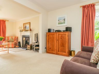 A living room with a sofa a wooden cabinet a television and a fireplace at Goshen Farm in St Agnes