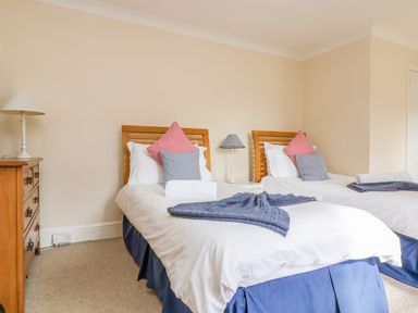 A bedroom with two single beds a wooden chest of drawers and two bedside lamps at Goshen Farm in St Agnes