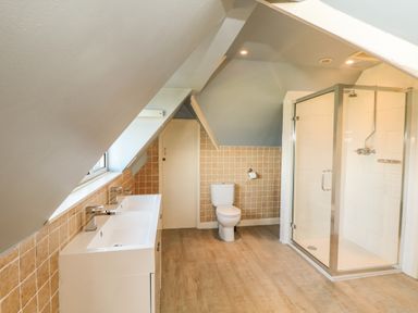 A bathroom with double sinks a toilet and a glass shower enclosure at Trelawns in Mawgan Porth