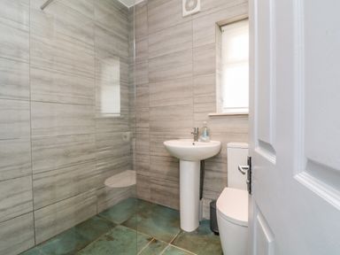A bathroom with a pedestal sink toilet and a glass shower enclosure at Trelawns in Mawgan Porth