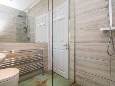 A bathroom with a walk-in shower towel radiator and a closed door at Trelawns in Mawgan Porth