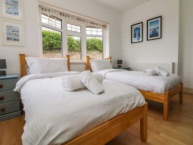 A bedroom with two single beds with white bedding and towels on them at Trelawns in Mawgan Porth
