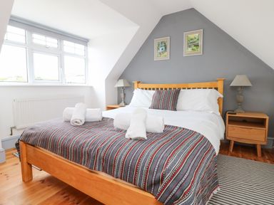 A bedroom with a wooden bed and striped bedding with white towels on it at Trelawns in Mawgan Porth