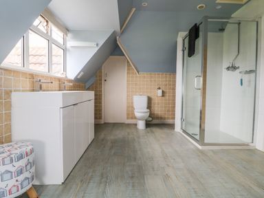 A bathroom with a double sink vanity a toilet and a glass shower at Trelawns in Mawgan Porth