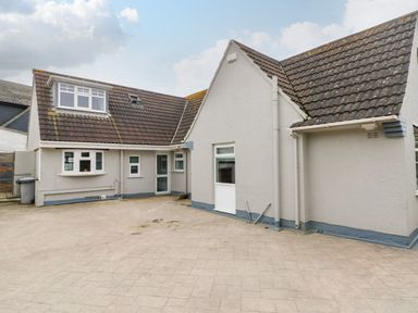 An exterior view of a house with tiled roof and paved courtyard at Trelawns in Mawgan Porth