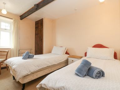 A bedroom with two single beds and blue towels on the beds at Parc An Castle Cottage in Lizard