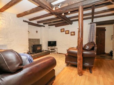A living room with leather sofas a wood burning stove and a television at Apple Loft in Lostwithiel