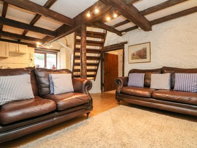 A living room with two leather sofas with striped cushions a rug and wooden stairs at Apple Loft in Lostwithiel