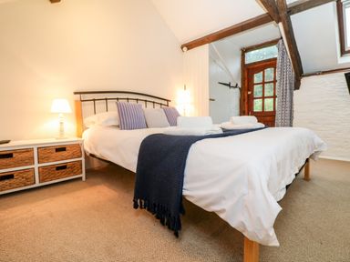 A bedroom with a bed pillows side table with lamp and baskets at Apple Loft in Lostwithiel