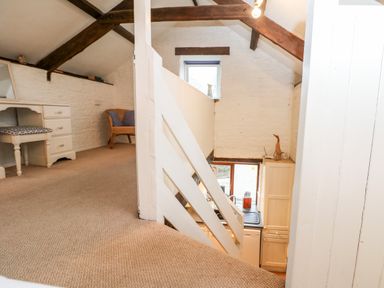 An upstairs area with a vanity table and chair overlooking a kitchen below at Apple Loft in Lostwithiel
