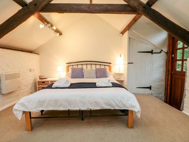 A bedroom with a bed towels lamps and a door at Apple Loft in Lostwithiel