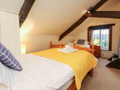 A bedroom with two single beds with yellow blankets and striped pillows at Apple Loft in Lostwithiel